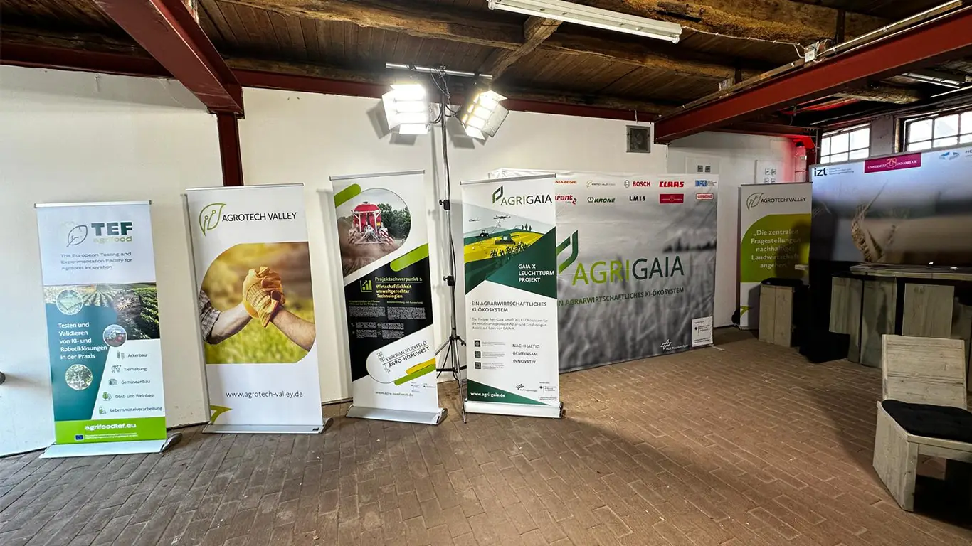 Kleiner, überdachter Innenbereich mit Roll-Ups und Bannerdisplays von Agri-Gaia, Agrotech Valley und TEF AgriFood. Der Fokus liegt auf Infomaterialien zu KI, Nachhaltigkeit und Robotik in der Landwirtschaft.